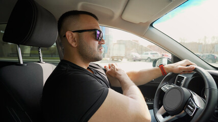Side portrait of handsome cruel serious young man sitting in car. A brutal man with a beard in a...
