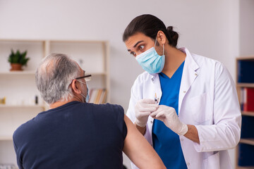 Old man visiting young doctor in covid-19 vaccination concept