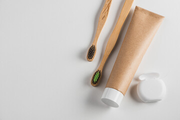 Top view on wooden toothbrushes, toothpaste and dental floss on white background