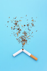 A broken cigarette with tobacco splash. Quit smoking concept. No tobacco day. Blue background, copy space.