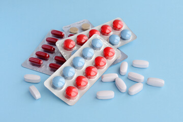 Assorted pharmaceutical medicine pills, tablets and capsules over blue background