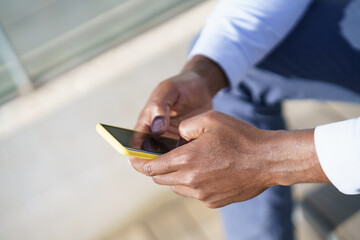 Hands of unrecognizable black man using a smartphone.
