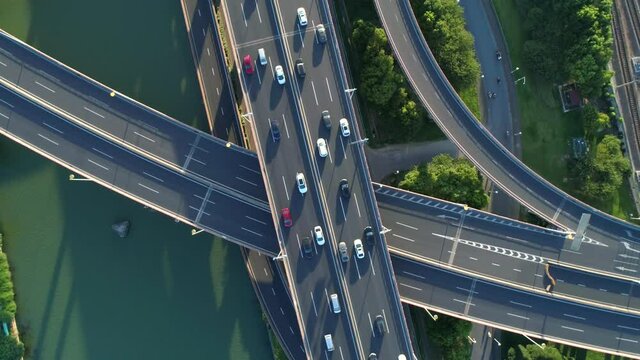 Aerial drone view of highway multi-level junction road with moving cars at sunset. Active movement of transport cars vehicles in different directions. China. Top down view, rotation shot.