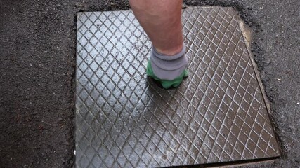 Man with green gloves and strong arm replaces manhole cover