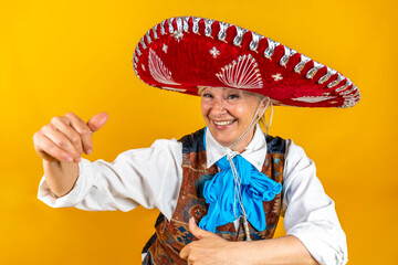 Funny portrait of mature woman. A beautiful lady with a sombrero dancing dressed as a Mexican mariach