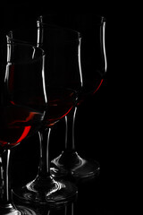 Bottle and glasses with red wine on a black background