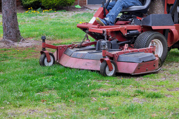 Man ride-on with lawnmower mows green grass