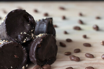 Chocolate tubes with filling and chocolate peanuts on wooden table top close up