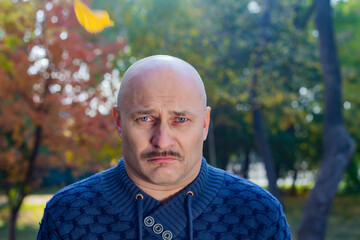 Portrait of a sad bald man in a blue sweater