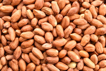 Many grains of organic peeled peanuts, close-up, top view.