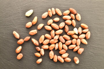 Organic peeled peanuts, on a slate board, close-up, top view.