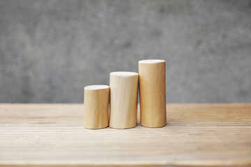 Thin and short barkless wooden log blocks on wooden table. Barkless cedar log set lined up closely together in order of height on wooden background. 