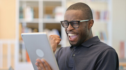 Fototapeta na wymiar Portrait of Young African Man Celebrating on Tablet