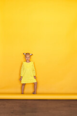 girl in a yellow dress on a yellow solid background. Full-length photo.