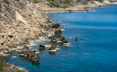 Obraz premium Rocky coastline with blue water and sky.