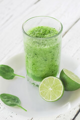 Healthy eating. Celery, spinach and lime smoothie. Drink glass, lime, spinach leaves. Vertical photo.