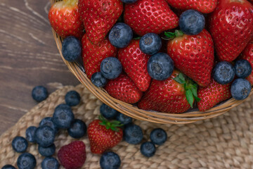 Strawberry and blueberry in basket on wood table. Close up berries.