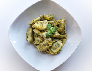 Vegetarian tortellini pasta with basil pesto, garnished with parmesan cheese.