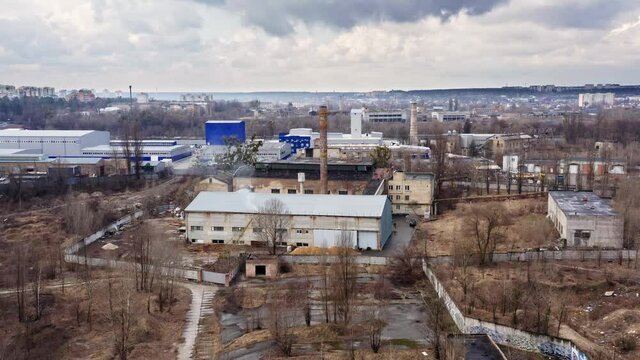 Drone shot of closed and not used factory warehouses. Aerial wide view of industrial zone from top. 