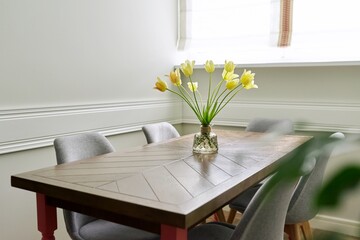 Vase with a bouquet of yellow tulips on a wooden table