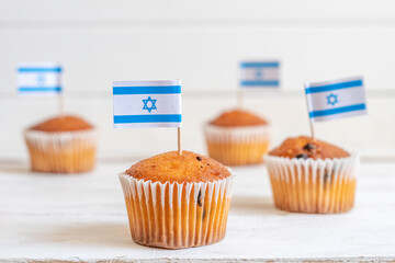 Cupcakes with Israeli flag toothpick topper decoration over white wooden background. Food for...