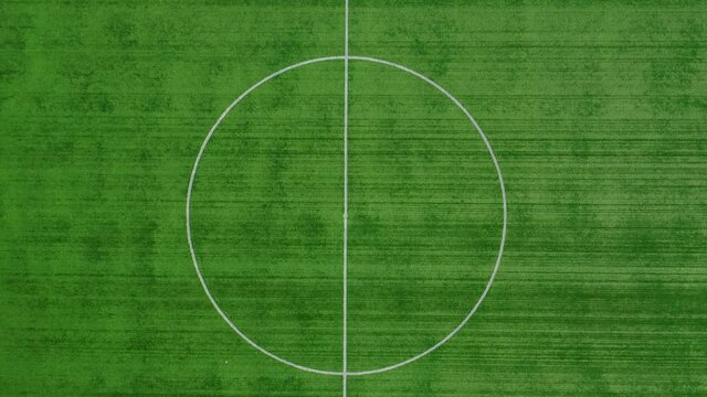 Green field of a new football stadium. Top view of the center of the field. Empty soccer field. Entertainment, sport concept. Zoom out. High quality.