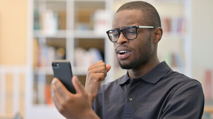 Obraz na płótnie Canvas Portrait of Upset Young African Man having Loss on Smartphone