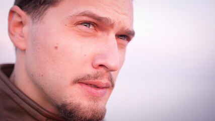 Macho attractive appearance handsome bearded troubled about something portrait. His blue eyes looking upset in sunset light