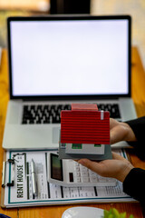 Close up wooden toy house with business woman signs a purchase contract or mortgage for a home, Real estate concept.	
