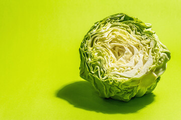 Obraz premium Fresh young cabbage, half a head in bright green background
