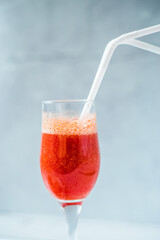 Close up freshly squeezed strawberry juice in a glass on a blue and summer background. Fruit cocktail with plastic tubes on the table. Empty space for text