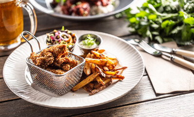 Fried crispy chicken wings with chips, dip and salad served on a table
