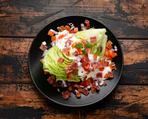 Iceberg wedge salad with bacon, cherry tomatoes, red onion and dressing. healthy food