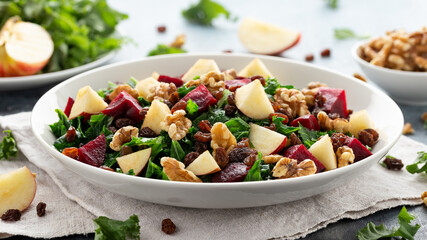 Kale salad with apple, beetroot, walnut and raisins in white plate. Healthy food
