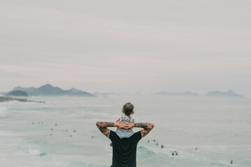 Father and daughter looking at the ocean and the mountains from above