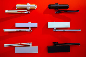 Door closers on a red background. Many different door and gate closers. Concept - sale of entry...