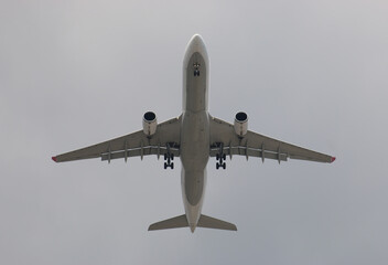 The plane landing on a background of gray and cloudy sky.