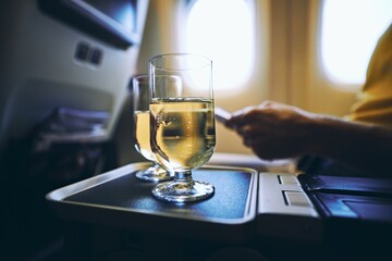 Dring during flight. Two drinking glasses of sparkling wine against airplane window.