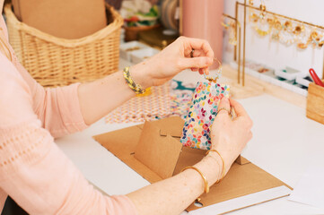 Woman packing handmade earrings, freelance job of artisanal jeweler artist