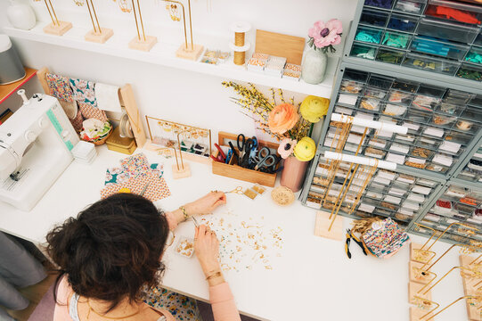 Jewelry designer working in studio, young woman creating handmade earrings, top view