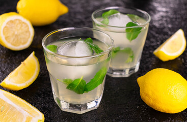 Lemonade with fresh lemon and mint on a black background.