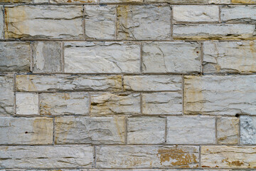 A fragment of a gray stone wall made of hewn stone of a rectangular shape.