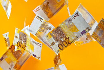 Yellow dollar bills on an orange background. 200 euro banknotes close up. Money flies in the air.