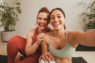 Cheerful female friends taking selife at yoga class