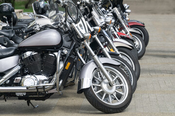 Fototapeta na wymiar Motorcycles parked on the motorcycles parking lot. Closeup of motorcycles front wheel.