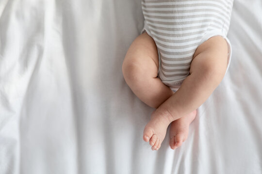 Cropped Image Of Little Baby In Diaper And Bodysuit Lying On Bed