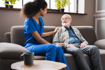 Nurse holding hand of senior man in rest home. Happy female caretaker assisting elderly old grandfather man. Picture of smiling nurse assisting senior grandpa