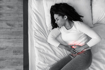 Black woman suffering from stomachache, touching her tummy
