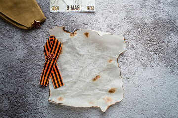 The holiday is May 9. St. George ribbon, cap and crumpled burnt paper for notes on the background...