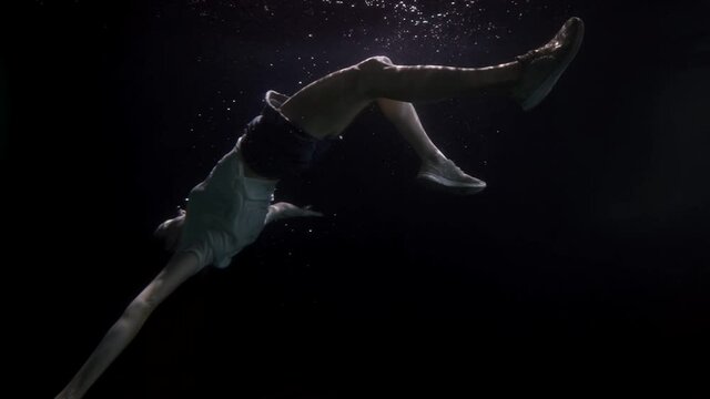 motionless and breathless female body is floating underwater, slow motion shot of sunken woman